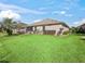 Spacious backyard with a lush green lawn, manicured landscaping, and a view of the home's exterior at 8662 Se 133Rd Ln, Summerfield, FL 34491