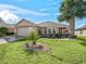 Inviting single-story home features a lush lawn with a decorative rock garden and mature palm tree at 8662 Se 133Rd Ln, Summerfield, FL 34491