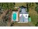Aerial view of a home with an in-ground pool, lush landscaping and a beautiful metal roof at 9210 County Road 48, Yalaha, FL 34797