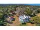 Expansive aerial view of a charming two-story home with a manicured lawn, outbuildings, and lush greenery at 9210 County Road 48, Yalaha, FL 34797