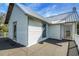Exterior view of the white home with a metal roof, featuring a spacious terrace and ample natural light at 9210 County Road 48, Yalaha, FL 34797
