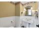 Charming half bathroom with pedestal sink and decorative wallpaper at 9210 County Road 48, Yalaha, FL 34797