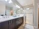 Well-lit bathroom with double vanity, tiled floors, and a glass-enclosed shower at 113 Bayou Bend Rd, Groveland, FL 34736