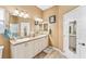 Bright bathroom features double sink vanity, large mirror and earth tone walls at 1555 Ward Ct, The Villages, FL 32162