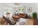 Bright living room with modern leather sofa, ceiling fan, and sunlit windows overlooking landscaped outdoors at 1616 Bayhill Dr, The Villages, FL 32159