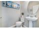 Powder room featuring a white toilet, a round mirror and pedestal sink at 17523 Promenade Dr, Clermont, FL 34711