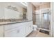 Bathroom featuring a double sink vanity, walk-in shower, and granite countertops at 17523 Promenade Dr, Clermont, FL 34711