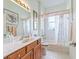 Cozy bathroom featuring a vanity with a sink, a mirror, and a shower-tub combination with curtains at 17652 Se 120Th Ter, Summerfield, FL 34491
