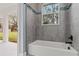 Clean bathroom with gray tile, bathtub, and backyard view at 18315 Dells Cv, Groveland, FL 34736