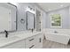 Modern bathroom with double vanity, freestanding tub, and gray tile at 18315 Dells Cv, Groveland, FL 34736