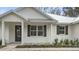 Farmhouse front porch with white exterior and dark shutters at 18315 Dells Cv, Groveland, FL 34736