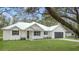 White farmhouse exterior with metal roof, landscaping, and large tree at 18315 Dells Cv, Groveland, FL 34736