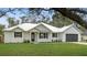 White farmhouse exterior boasts metal roof, shutters, and landscaping at 18315 Dells Cv, Groveland, FL 34736