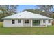 White house with metal roof, sliding glass doors, and grassy backyard at 18315 Dells Cv, Groveland, FL 34736