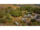 This aerial view shows a home with a spacious yard surrounded by lush green trees and open fields at 18415 County Road 33, Groveland, FL 34736