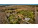 This aerial view shows a home surrounded by green trees and open fields with a long road nearby at 18415 County Road 33, Groveland, FL 34736