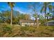 Exterior shot of the rear of a bright, quaint home with palms and a patio set at 18415 County Road 33, Groveland, FL 34736