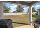 Covered back patio overlooking a large, well-maintained backyard with white fence and grill at 2455 Hastings Blvd, Clermont, FL 34711
