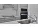 A modern kitchen featuring gray cabinets, stainless steel appliances, and white quartz countertops at 2854 Supermarine Rd, Tavares, FL 32778
