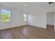 Sunlit bedroom featuring wood-look floors, two large windows, and neutral decor at 2932 Supermarine Rd, Tavares, FL 32778