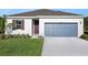 Home exterior featuring well-kept lawn, two-car garage, and colorful front door and window shutters at 2932 Supermarine Rd, Tavares, FL 32778