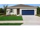 Charming single-story home with a well-manicured lawn, blue garage door, and neutral-colored exterior at 2950 Supermarine Rd, Tavares, FL 32778