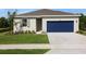 Charming single-story home with a well-manicured lawn, blue garage door, and neutral-colored exterior at 2950 Supermarine Rd, Tavares, FL 32778