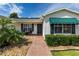 Charming single story home with beautiful landscaping, brick walkway and dark green awnings at 3218 Woodridge Dr, The Villages, FL 32162
