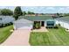 Well-maintained front yard featuring lush green grass, brick walkway, mature plantings and an attached garage at 3218 Woodridge Dr, The Villages, FL 32162