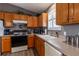Well-equipped kitchen with oak cabinets, gray countertop, and white appliances for your cooking needs at 3218 Woodridge Dr, The Villages, FL 32162