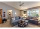 Living room featuring gray couches, a glass coffee table, and bright, natural lighting with the view through plantation shutters at 3218 Woodridge Dr, The Villages, FL 32162