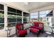 Bright sunroom with red seating, ceiling fan, and large windows offering views of the landscaped exterior at 3218 Woodridge Dr, The Villages, FL 32162