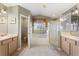 Bright bathroom with dual sinks, soaking tub, walk-in shower, and ceramic tile flooring at 3310 Osprey Hill St, Clermont, FL 34714