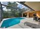 Enclosed pool area with clear blue water, covered patio with sofa, and plenty of seating for relaxation at 3310 Osprey Hill St, Clermont, FL 34714