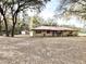 Exterior of single-story home with red metal roof and a separate garage, surrounded by trees at 37807 Felkins Rd, Leesburg, FL 34788
