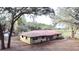 Exterior of a one-story home with a red metal roof and separate garage surrounded by mature trees at 37807 Felkins Rd, Leesburg, FL 34788