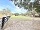 Large, partially-fenced front yard with mature trees and distant structures, offering a serene country setting at 37807 Felkins Rd, Leesburg, FL 34788