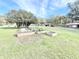 A large yard featuring garden beds, trees, and surrounding buildings at 37807 Felkins Rd, Leesburg, FL 34788