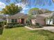 Charming single-story home featuring a well-manicured lawn, lush landscaping, and a two car garage at 3812 Westerham Dr, Clermont, FL 34711
