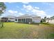 A view of the backyard with a screened-in patio, a well-manicured lawn, and privacy landscaping at 5095 China Sea Dr, Tavares, FL 32778