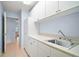 Laundry room features tile flooring, a stainless sink and lots of white cabinets for storage at 5095 China Sea Dr, Tavares, FL 32778