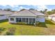 Rear exterior showing a single-story home with a screened-in lanai, and a well-maintained lawn on a sunny day at 5095 China Sea Dr, Tavares, FL 32778
