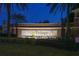 Community entrance sign illuminated at dusk, framed by palm trees and greenery at 525 Narrow View Ln, Groveland, FL 34736