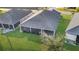 Overhead view of a screened-in back patio, a lush lawn and garden, and the dark roof of a charming single-story home at 5819 White Ibis, The Villages, FL 32163