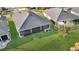 Overhead view of a screened-in back patio, a lush lawn and garden, and the dark roof of a charming single-story home at 5819 White Ibis, The Villages, FL 32163