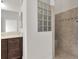 Bathroom with dark wood vanity and walk-in shower with neutral tile and glass block window at 5819 White Ibis, The Villages, FL 32163