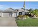 Charming single-story home featuring a well-manicured lawn, tropical landscaping, and a spacious two-car garage at 5819 White Ibis, The Villages, FL 32163