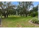 Expansive backyard with mature trees offering shade and a serene view of the waterway at 5910 Lake Emma Ct, Groveland, FL 34736