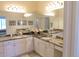 Bathroom vanity featuring granite countertops, dual sinks, and ample lighting at 10177 Mainsail Dr, Oxford, FL 34484