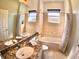 Bright bathroom featuring double sinks, granite countertops, and a tub with tiled surround at 10177 Mainsail Dr, Oxford, FL 34484